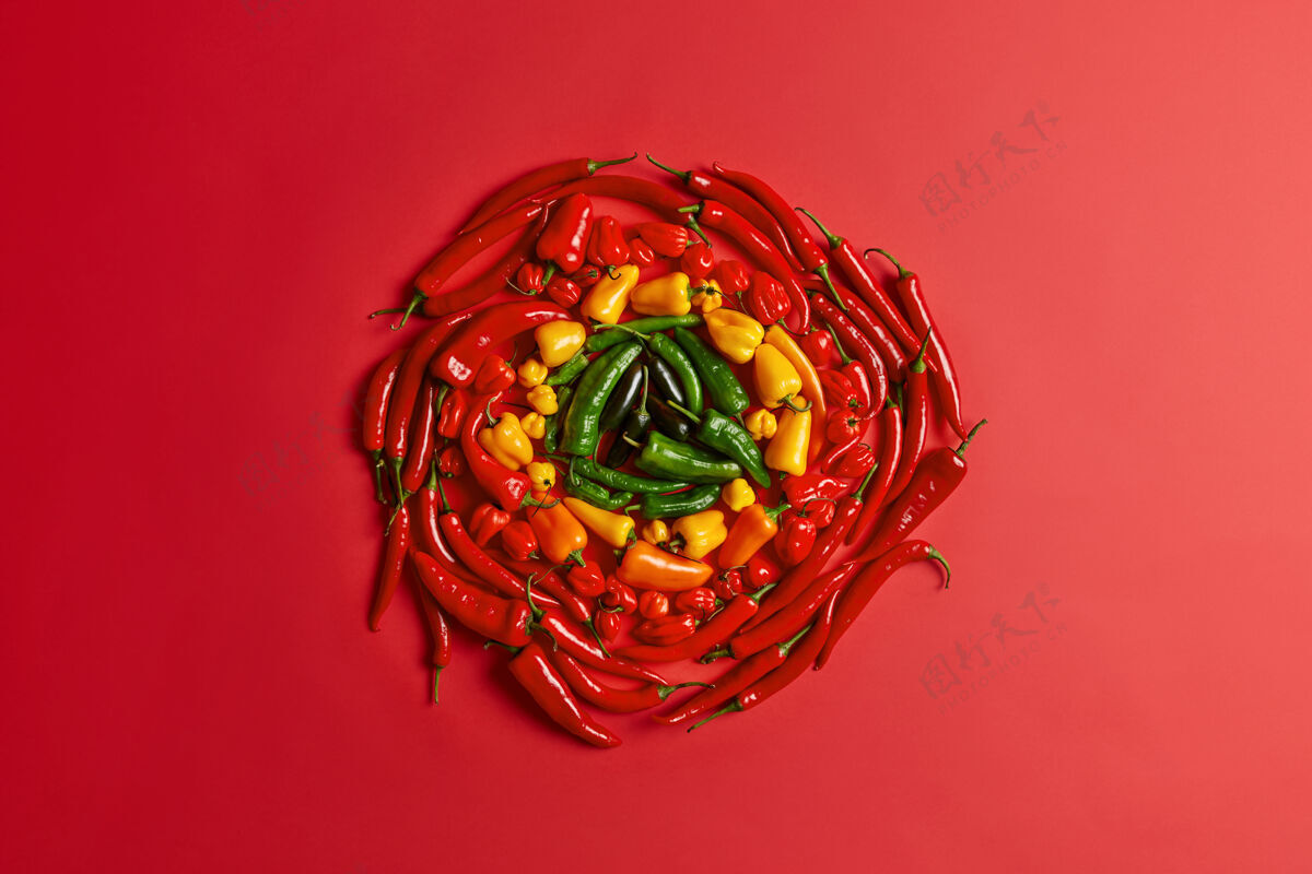 香料红黄绿相间的花椒在红色的背景上呈圆形排列 五颜六色的新鲜蔬菜 高角度的视角 创意的布局 辛辣的调味辣椒 素食的理念 丰富的品种辣有机顶部
