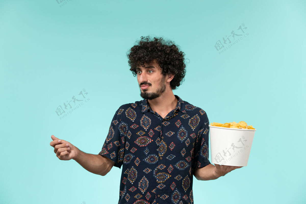 电影正面图：年轻人拿着篮子 拿着土豆 放在蓝色的桌子上 看电影男人土豆风景