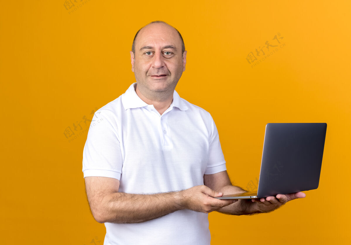 成熟喜欢随意的成熟男人拿着笔记本电脑隔离在黄色的背上休闲手持请