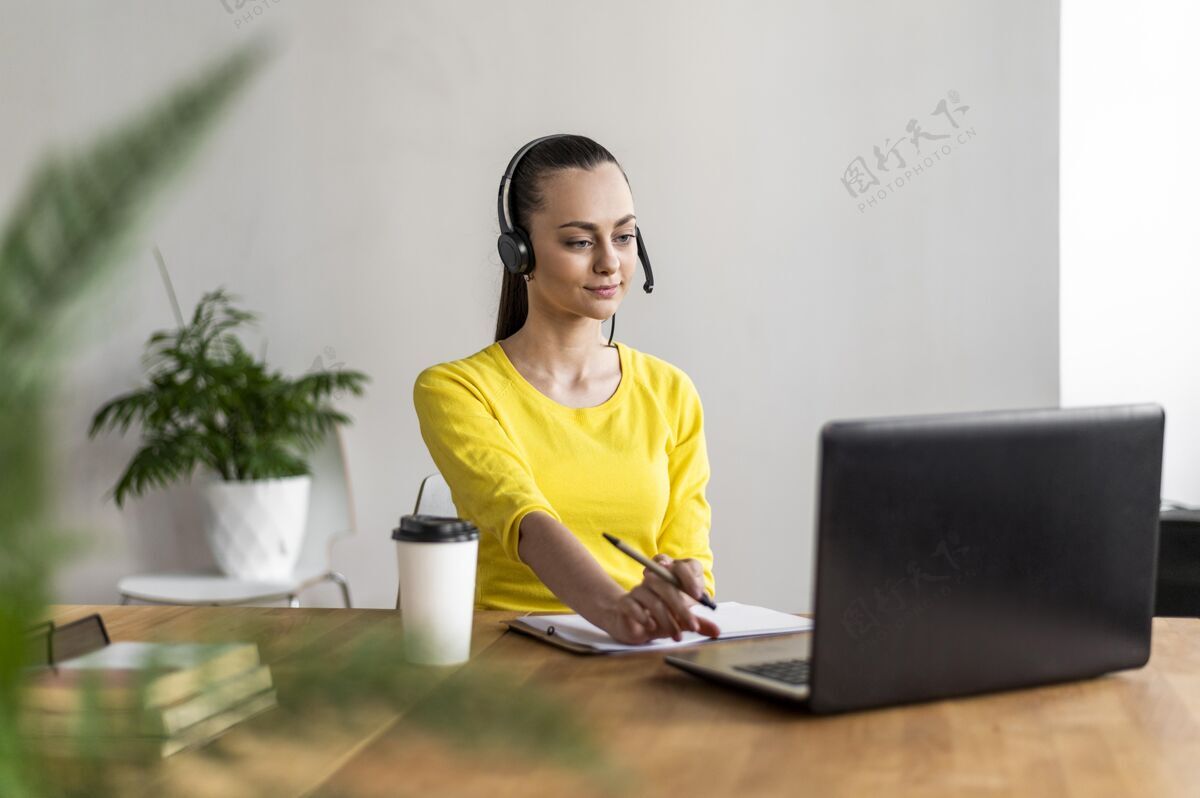 工作工作中的肖像女性有视频通话笔记本电脑办公桌耳机