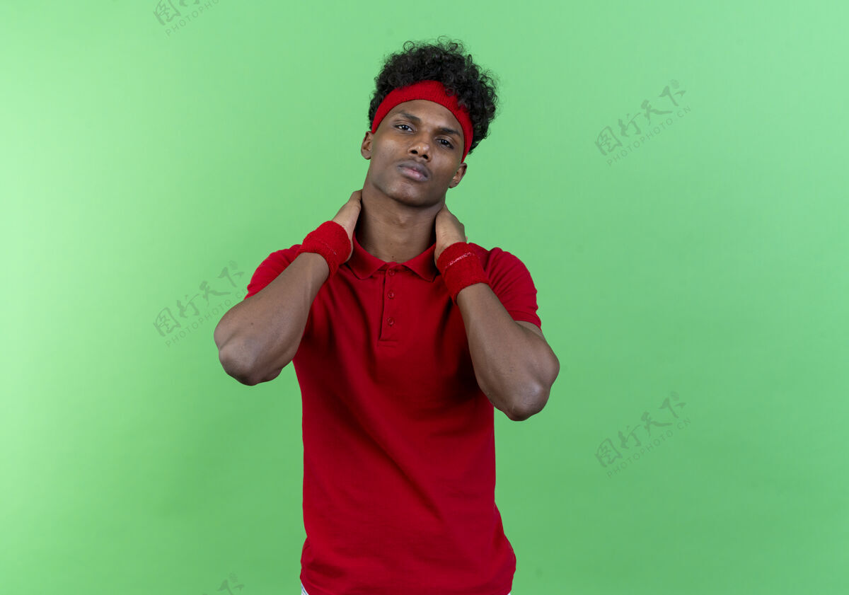 头带自信的年轻美国黑人运动男子戴着头带和腕带保持手在脖子后面隔离绿色背景年轻脖子腕带