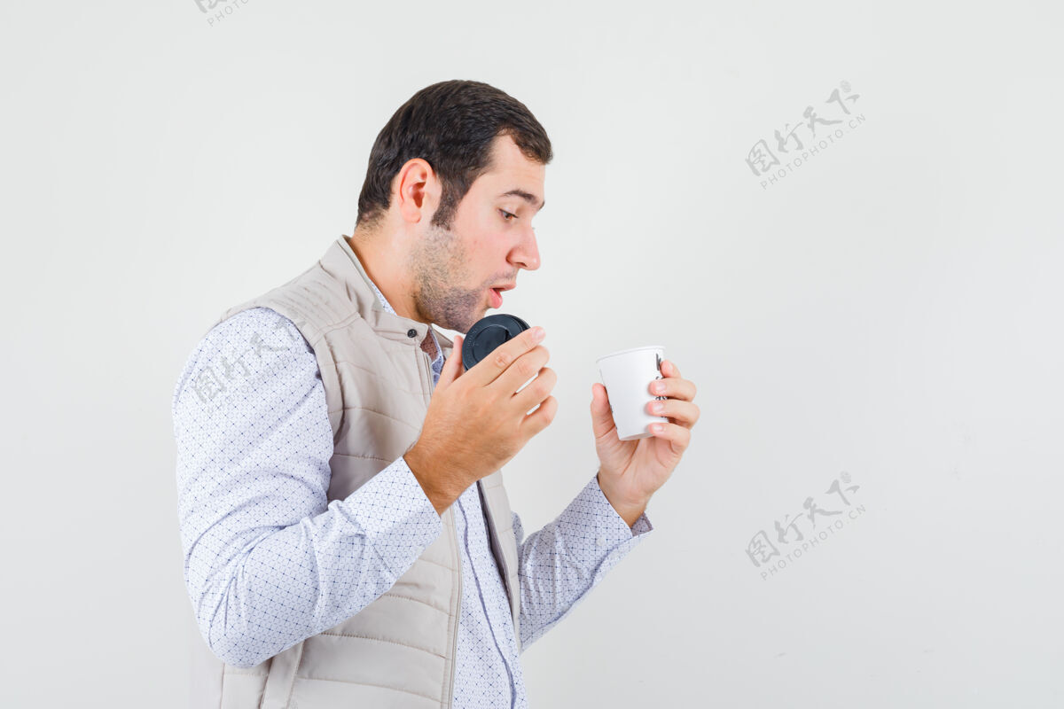 肖像年轻人拿着一杯外卖咖啡 穿着米色夹克试图打开它 目光集中正视图优雅外卖男人