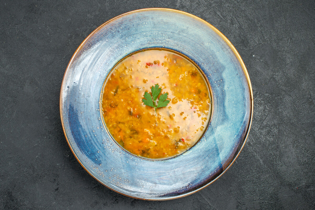 汤碗顶部特写查看汤和草药汤在蓝色盘子上的桌子草药食物汤