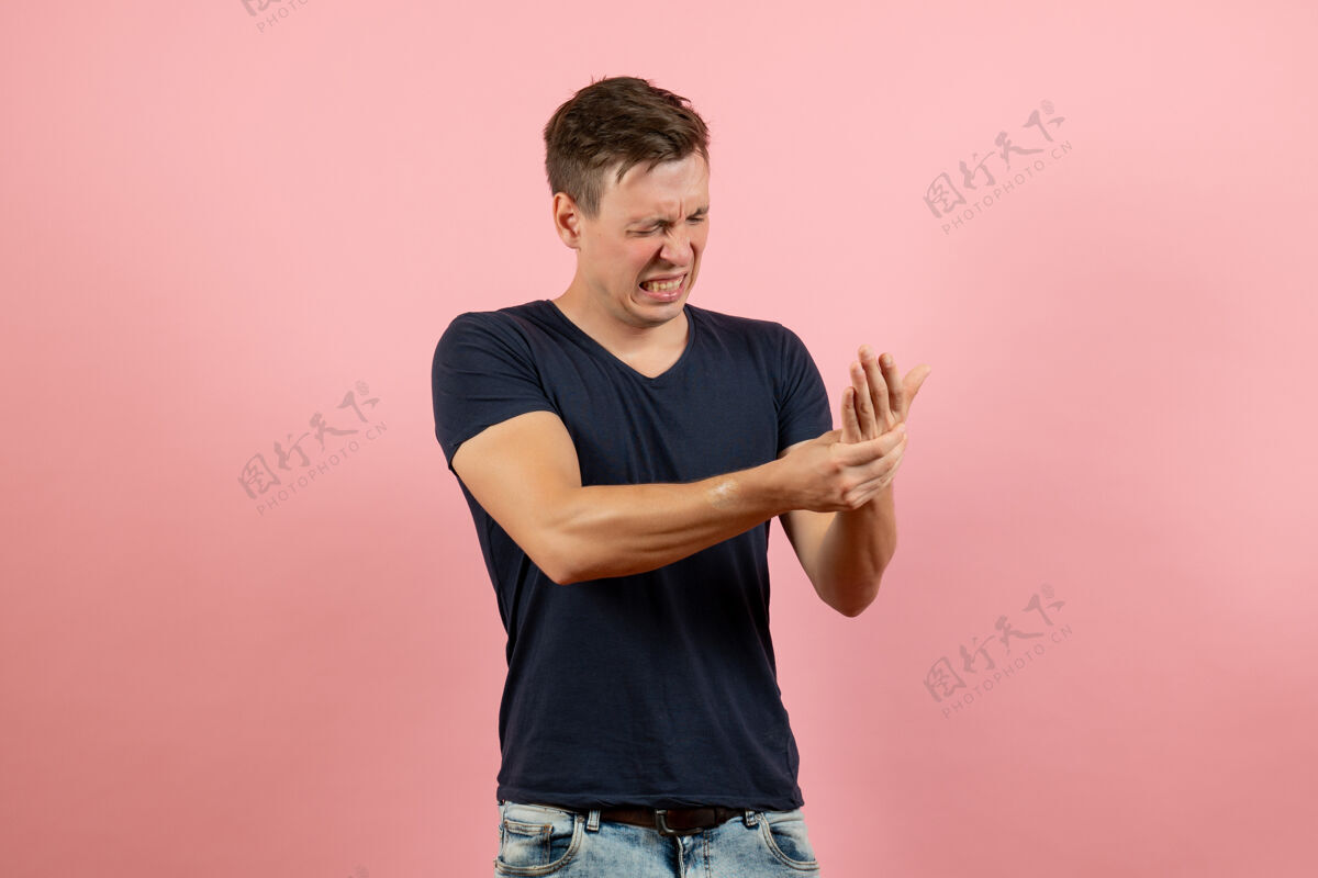 男性正面图身着深蓝色衬衫的年轻男性在粉色背景上手臂受伤男性模特彩色情感男受伤肖像人