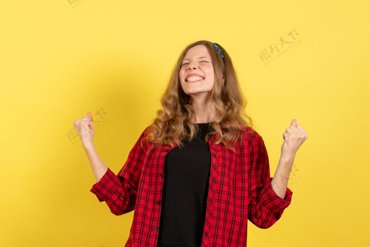 女孩正面图身着红色格子衬衫的年轻女性站在黄色背景上欢呼雀跃的人色模特女郎成人年轻女性衬衫