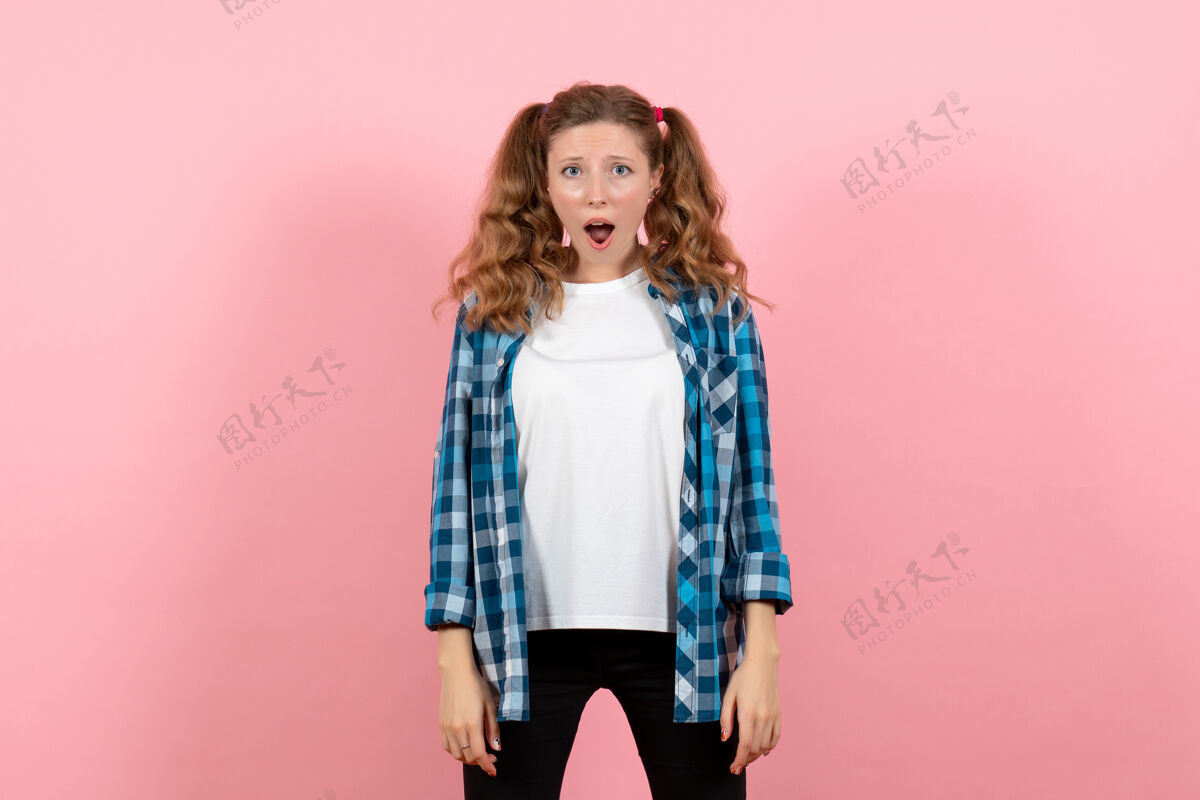 成人正面图穿着格子衬衫的年轻女性在粉色背景上摆姿势年轻女性彩色情感模特儿漂亮衬衫格子