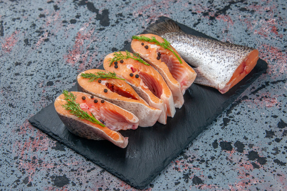 美食侧视图新鲜切割生鱼绿色深色托盘上蓝黑色混合颜色表与自由空间菜肴托盘肉