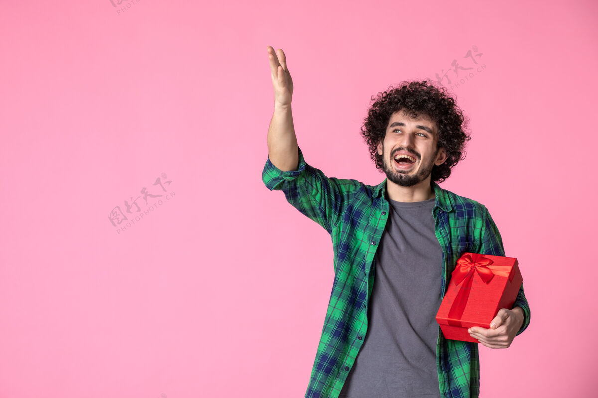 红色包装浅粉色墙上红色包裹的年轻男性正面图衬衫盒子休闲