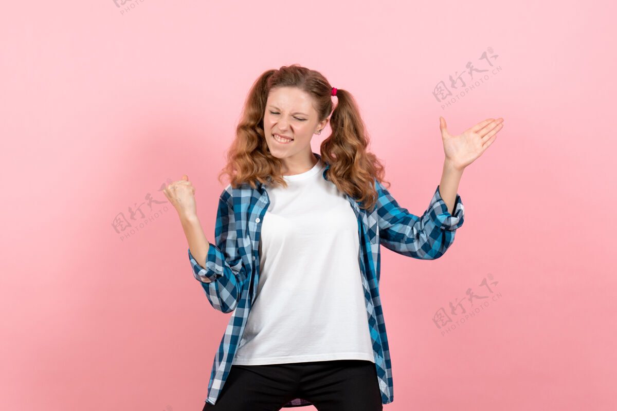 情感正面图身着格子衬衫的年轻女性在浅粉色背景上摆姿势模特女性情感儿童青春色彩孩子年轻女性浅粉色