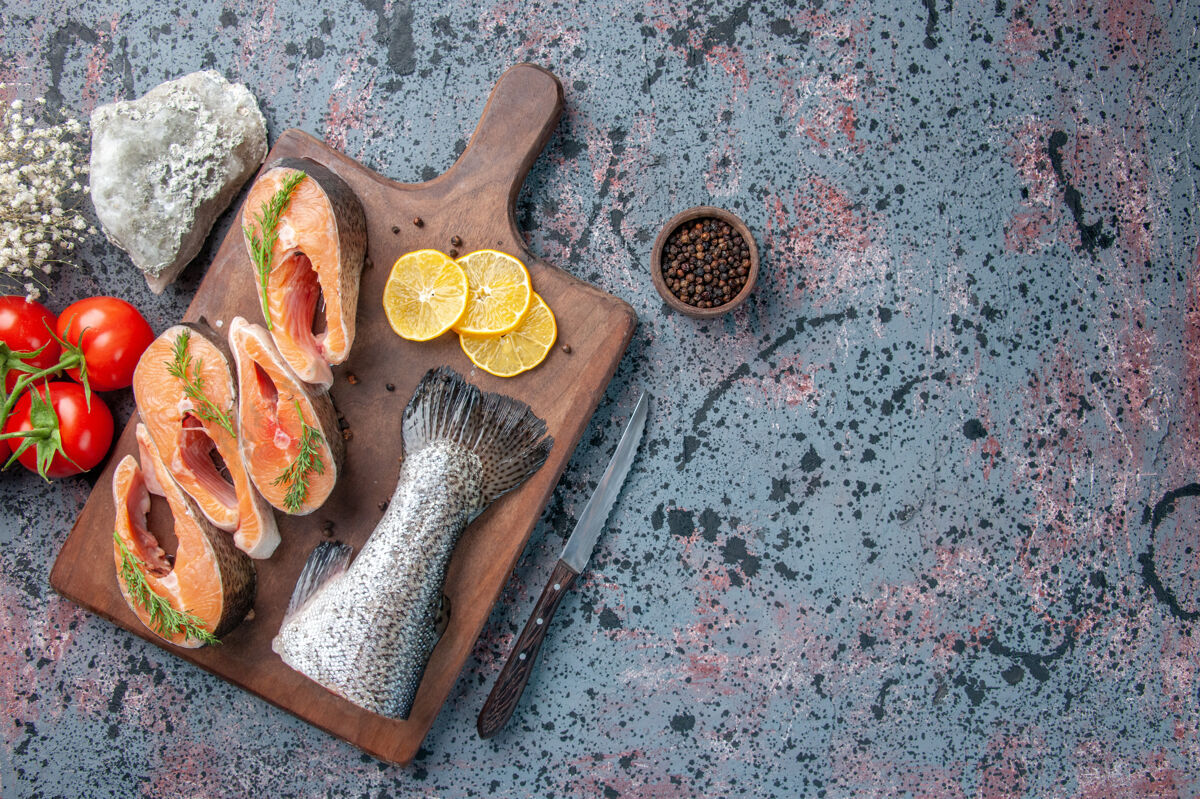 传统俯瞰图新鲜的鱼柠檬片绿色胡椒在木制砧板和刀子上蓝黑色混合颜色表切割勺子木勺