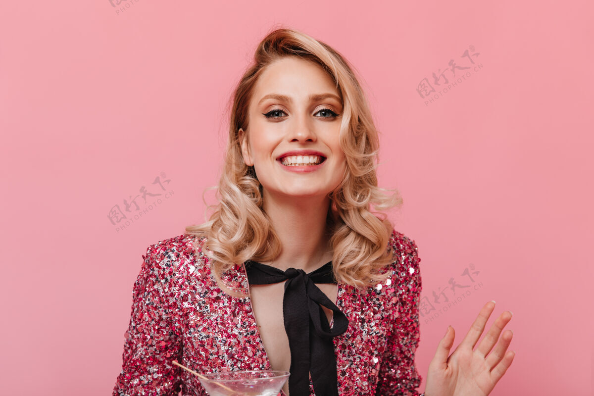 时尚快乐的女人穿着闪亮的上衣 打着蝴蝶结 在粉红色的墙上微笑肖像黑发年轻