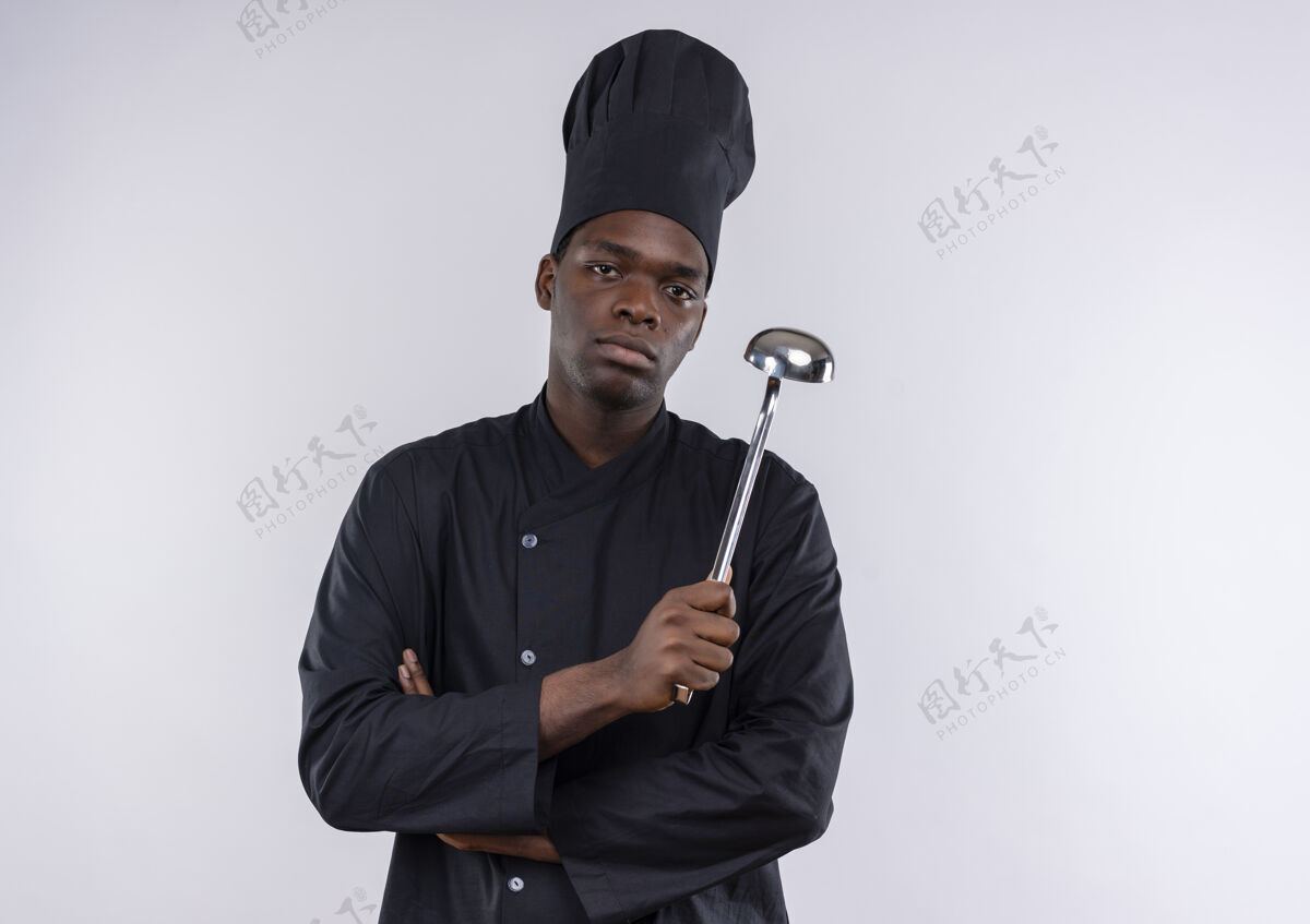 烹饪年轻自信的非洲裔美国厨师身着厨师制服 双手交叉握着勺子放在白色的空间里信心空间手臂