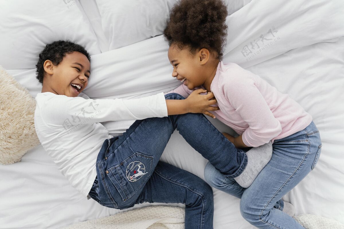 家庭两个兄弟姐妹一起在家里的床上玩耍的俯视图在一起孩子顶视图