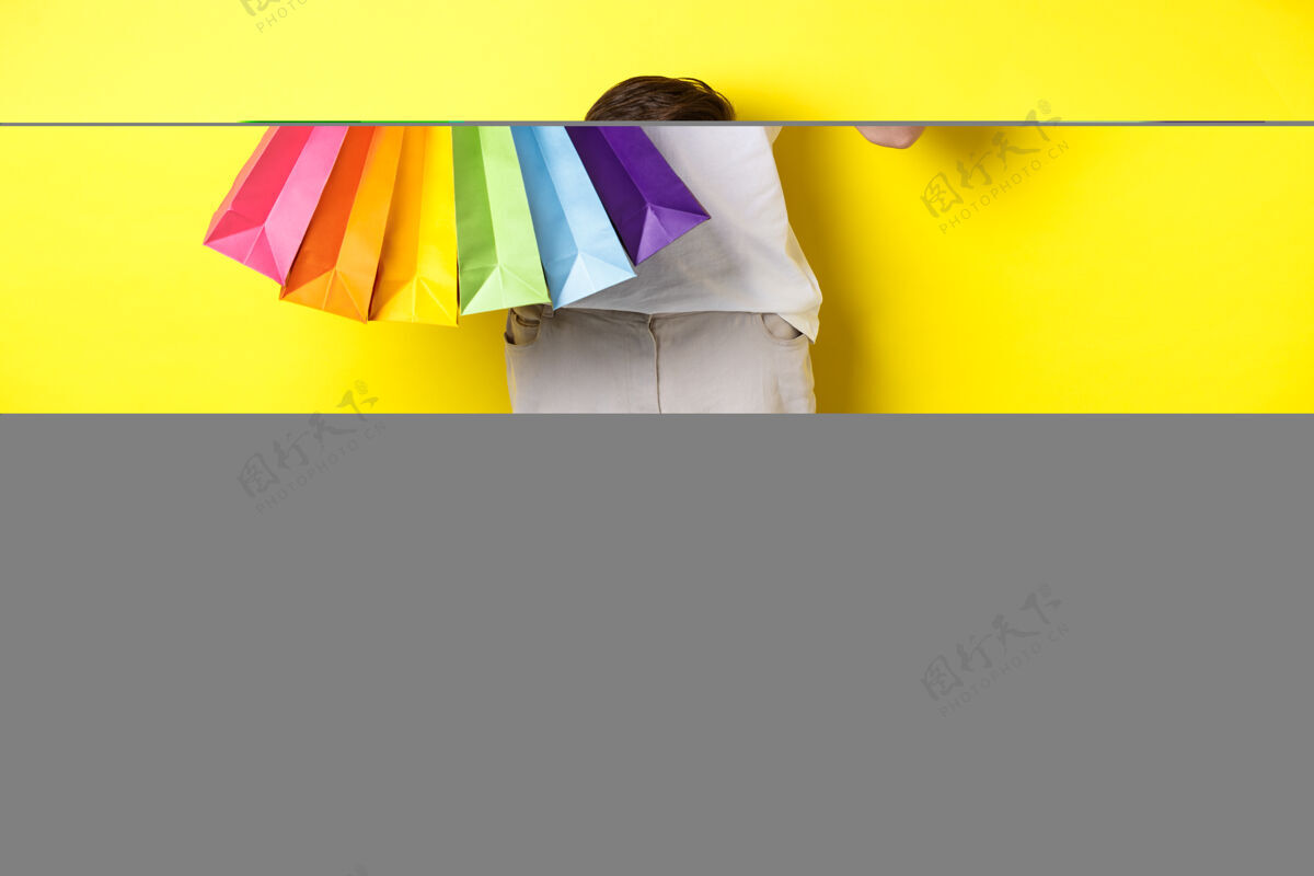 购物袋年轻人拿着购物袋 展示着手机屏幕 汇款单 站在黄色的背景上年轻黄色时尚
