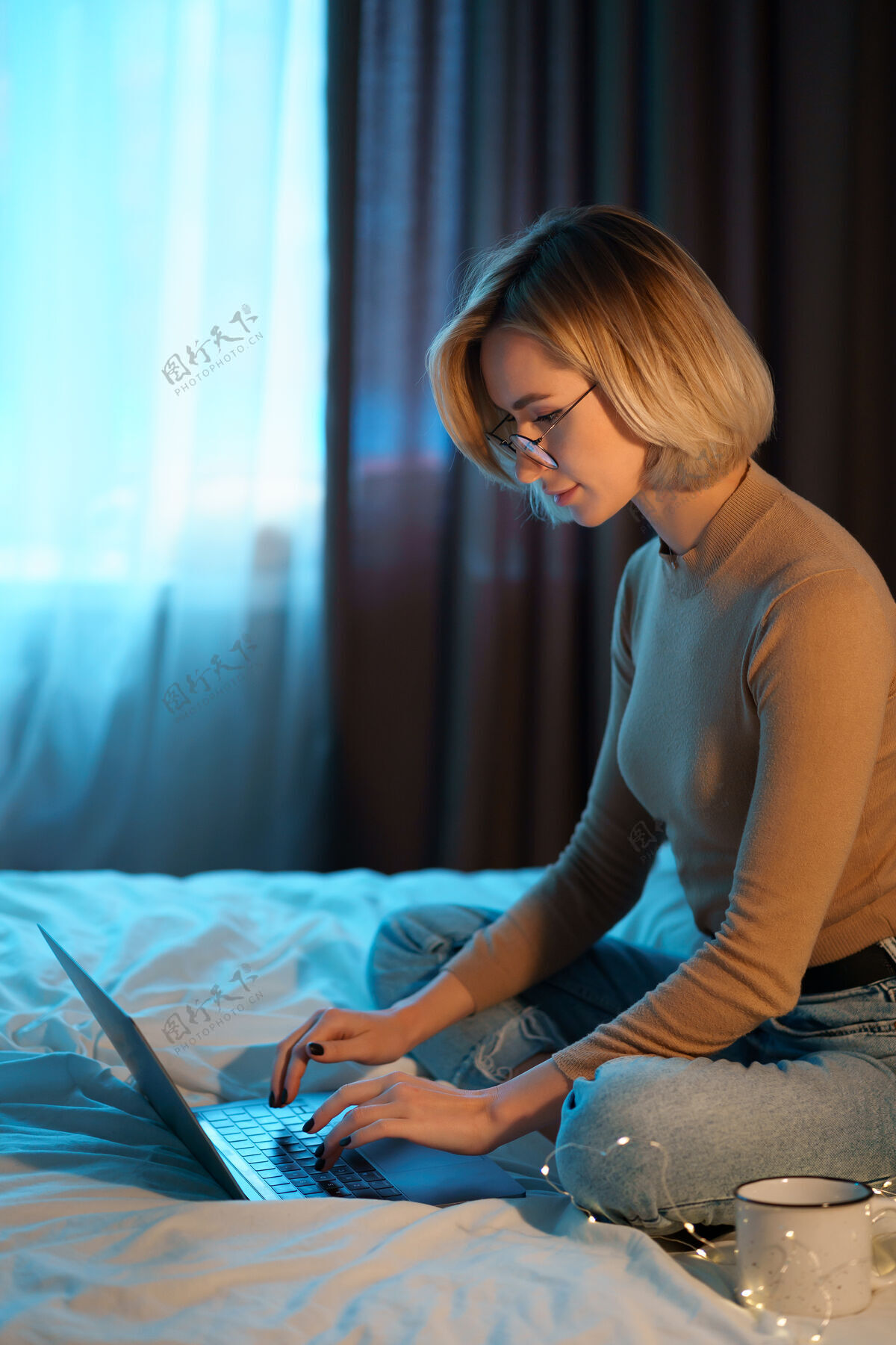 电脑一个金发短发的女人穿着牛仔裤躺在白色的床上 手里拿着一台笔记本电脑互联网自由职业者工作