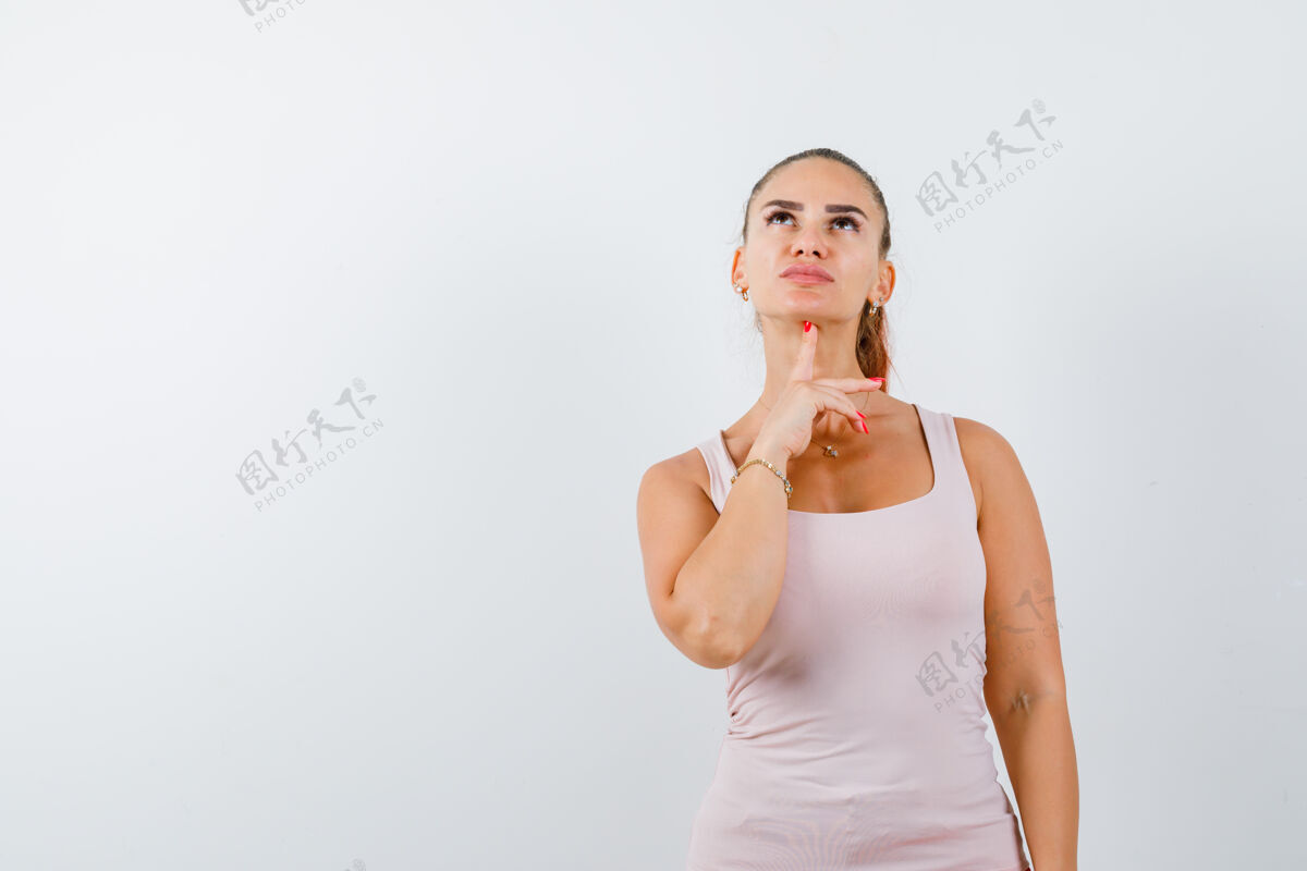 新鲜年轻的女性拿着手指放在下巴下面 同时在单打中抬起头 显得犹豫前视图肖像持有人