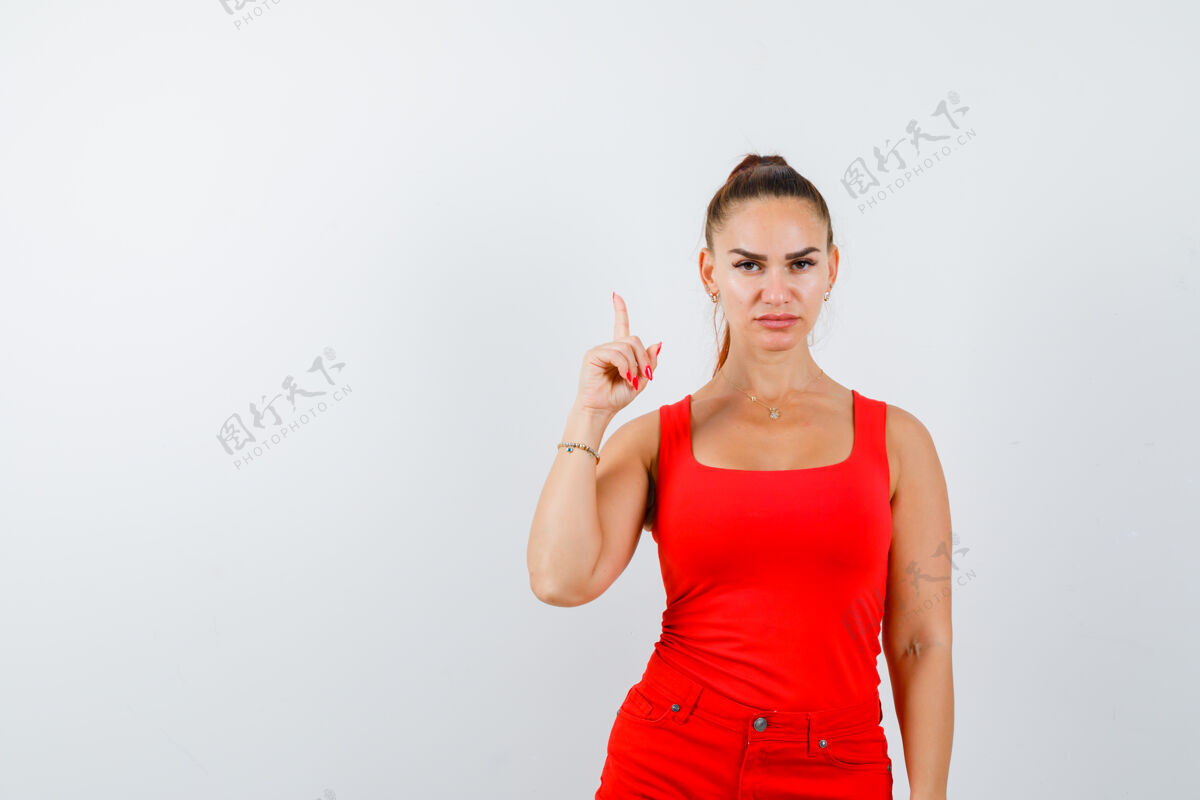 中风年轻的女士指着红衬衫 红裤子 看起来很自信 正面视图柔软裤子干净