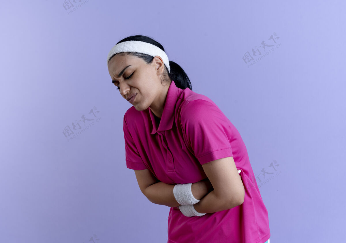 腕带年轻疼痛的高加索运动女性戴着头带和腕带 腹部呈紫色 留有复制空间女人复制佩戴