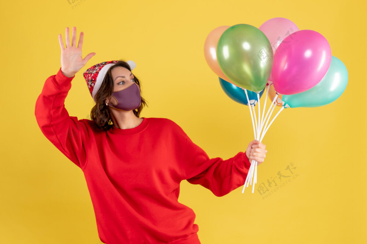 年轻女人正面图年轻女子拿着气球 戴着黄色的无菌面具外科口罩派对气球