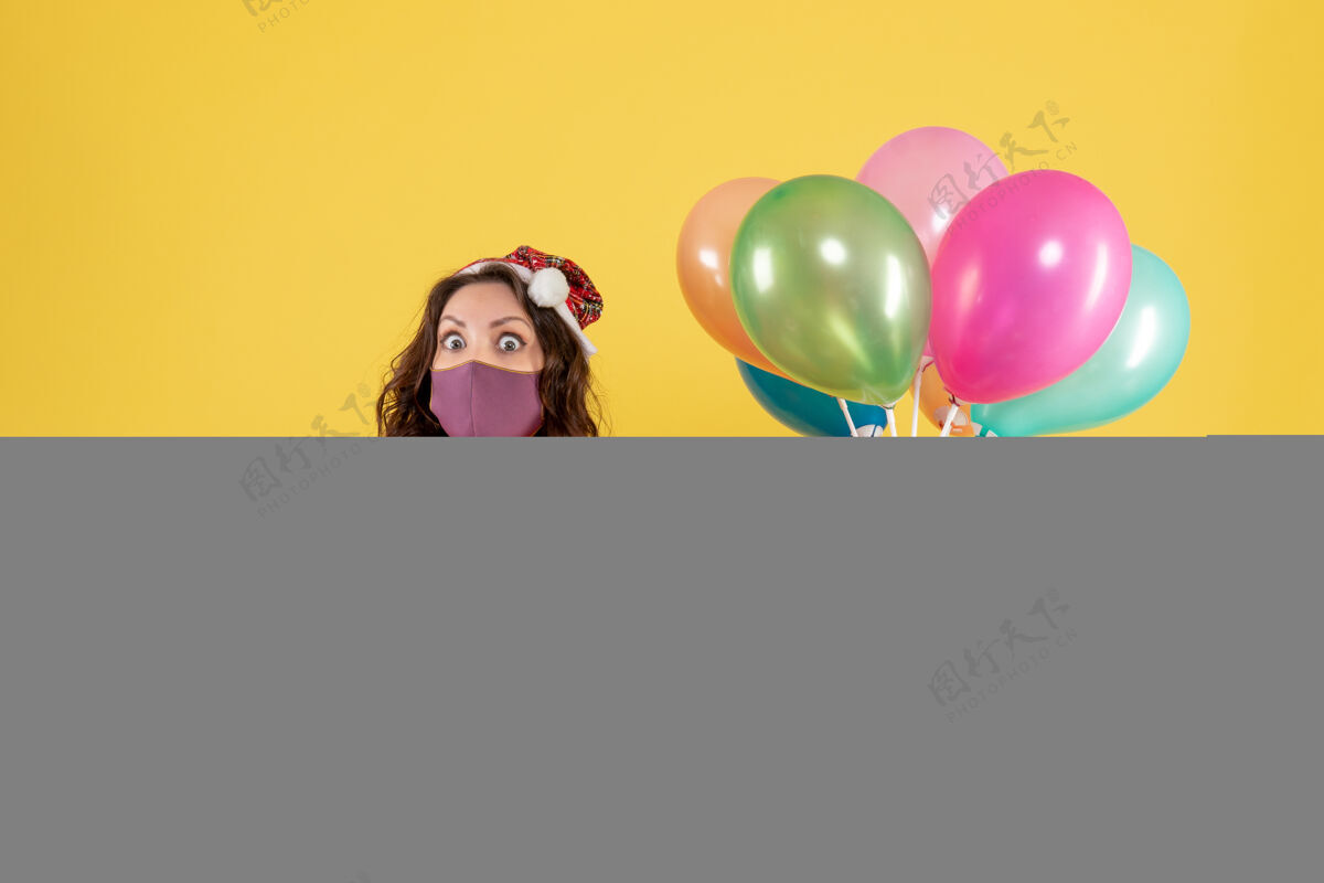 情感正面图年轻女子拿着气球 戴着黄色的无菌面具外科口罩绝育气球