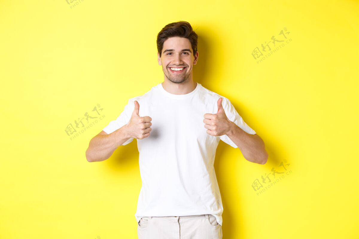 成年人快乐的人竖起大拇指表示赞同 像某事或同意 站在黄色背景上模特认可男人
