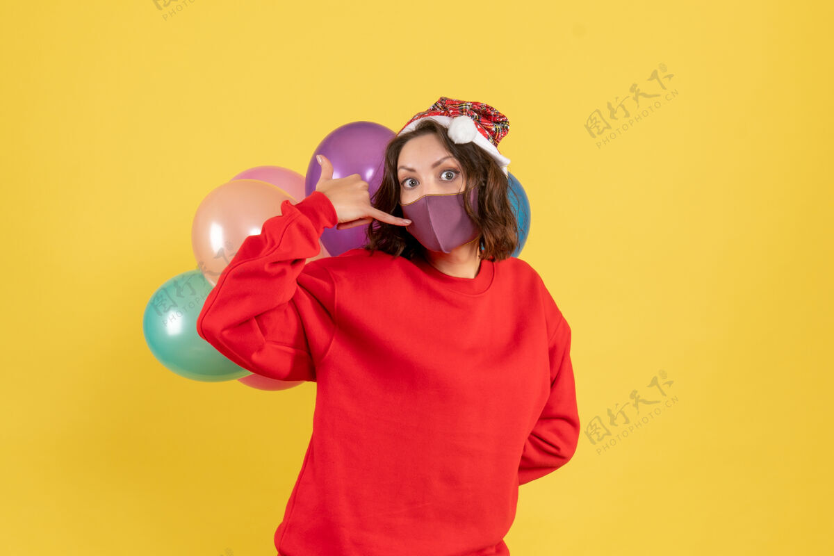 颜色正面图年轻女子藏在黄色无菌面具气球正面孩子年轻女人