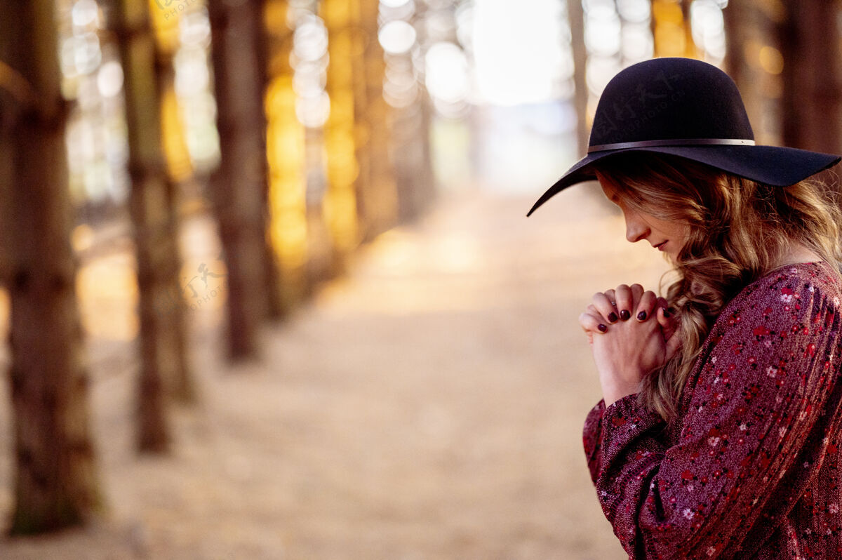 卷发戴黑帽子的年轻女子在祈祷女人帽子年轻