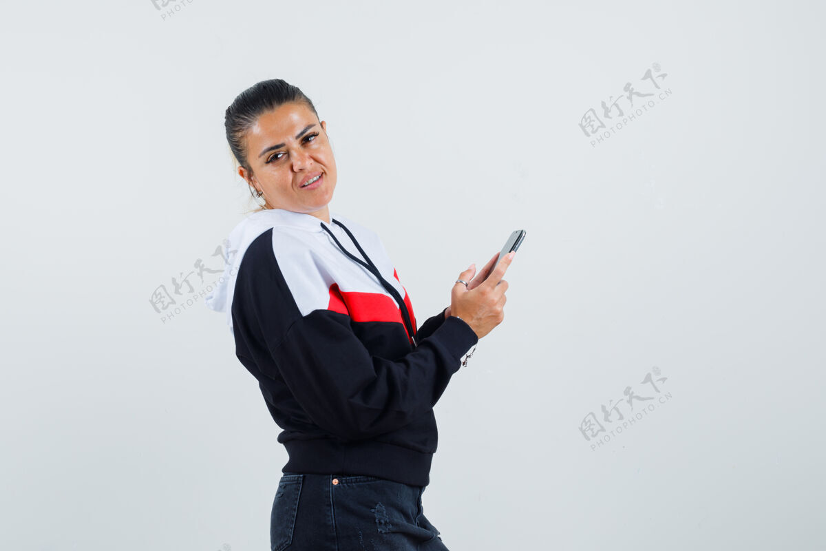 前面年轻女性一边看一边拿着彩色运动衫正面的手机旁边黑发五颜六色