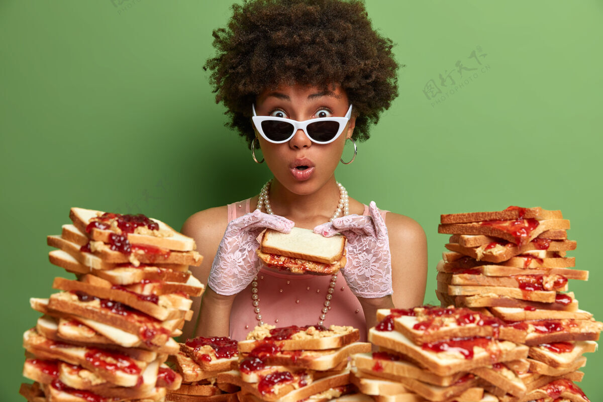 卡路里迷人的女人 有着非洲头发 周围是花生酱果冻三明治印象惊讶魅力