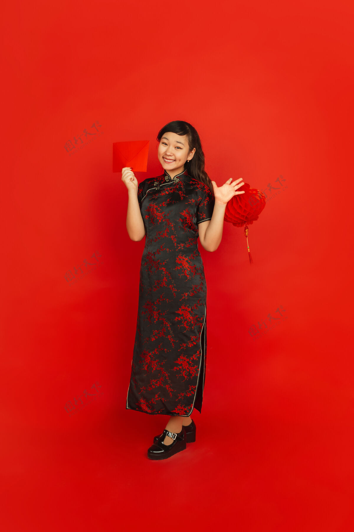 欢呼年轻的亚洲女人拿着红包和中国灯笼隔离在红墙上庆祝节日快乐