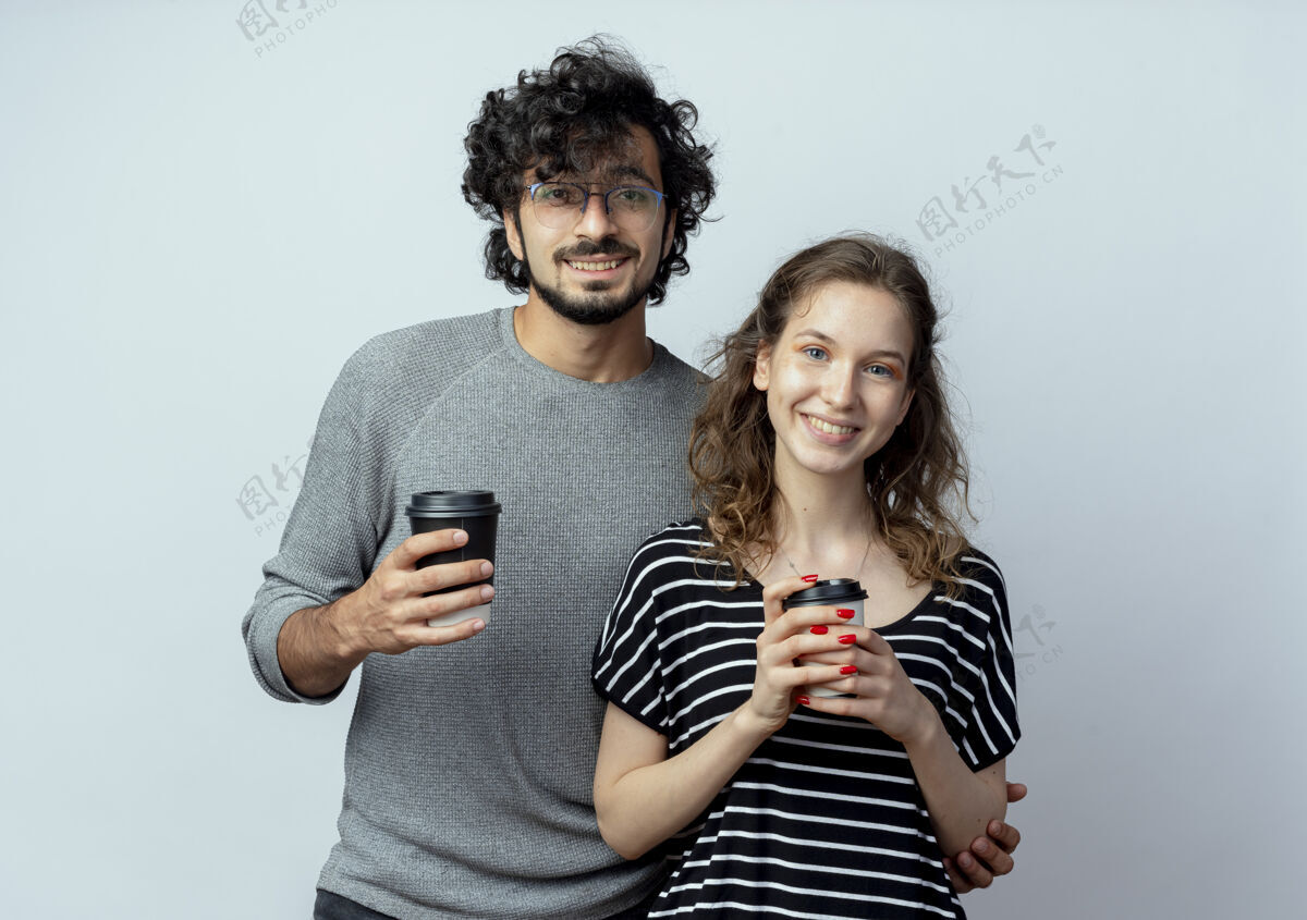 女人一对快乐的年轻夫妇站在白墙上 手里拿着手机 脸上洋溢着幸福的笑容男人夫妻移动