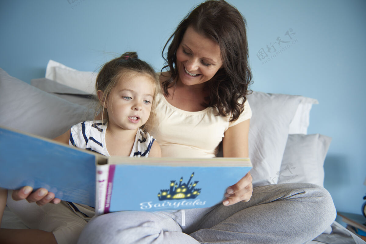 拥抱妈妈和女儿在读童话故事教育护理家庭生活
