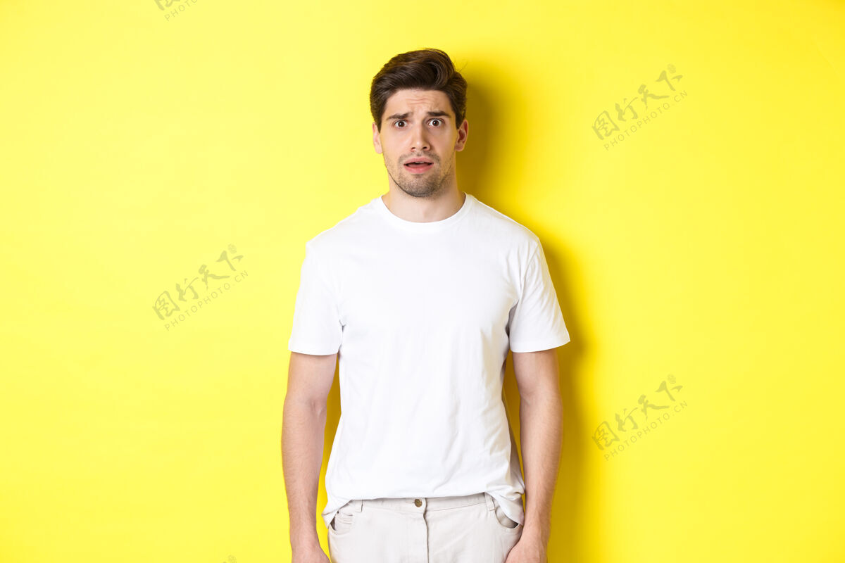 表情一个困惑而紧张的男人看着奇怪的东西 皱眉焦虑 站在黄色的背景下模特帅气自信