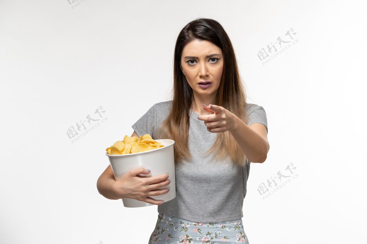 前面正面图年轻女性手持薯片 在浅白的表面上看电影浅白色电影院遥远