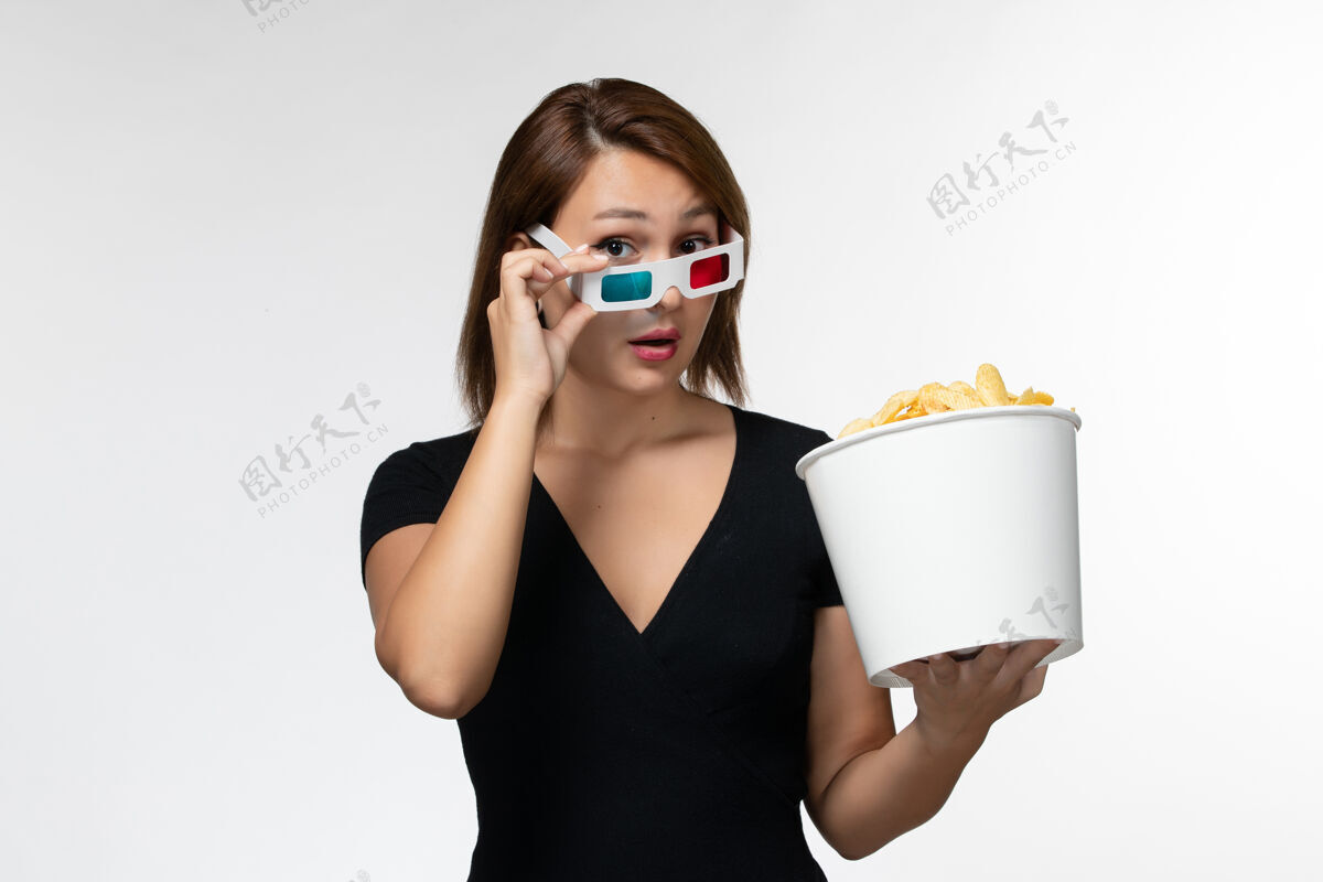 举行正面图：浅白色表面上戴着d型太阳镜拿着薯片的年轻女性美丽孤独前面