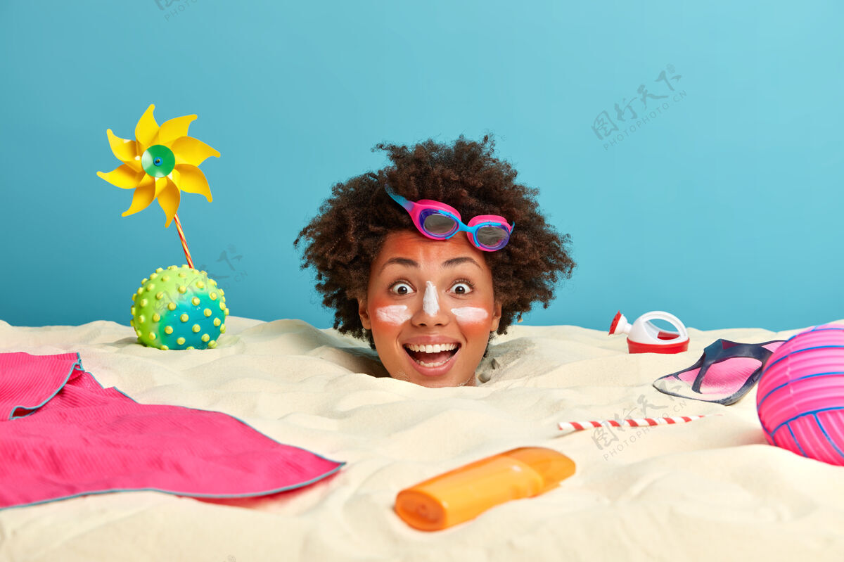 女人年轻女子头上涂着防晒霜 脸上围着沙滩饰品假日埋葬玩具