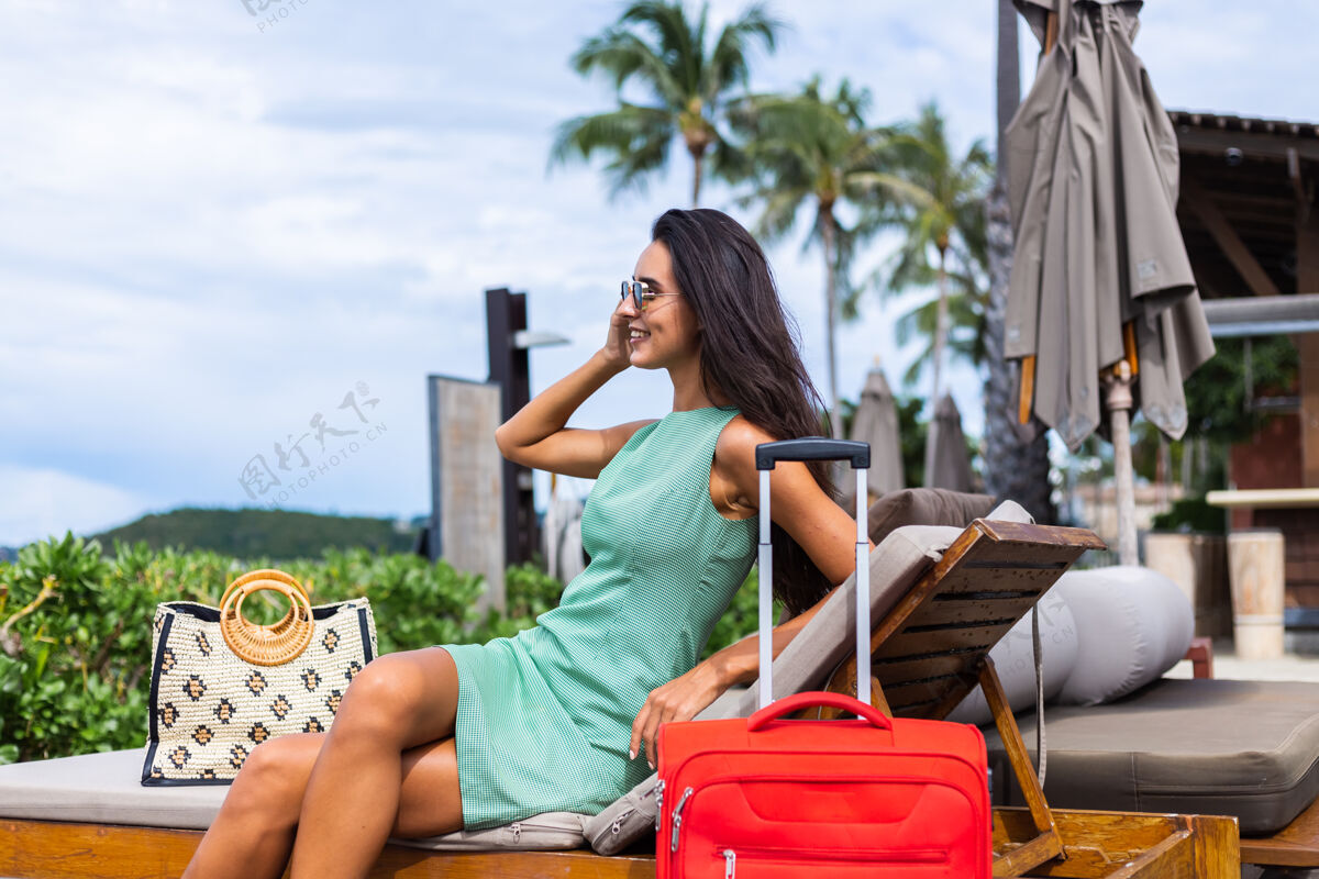 旅游快乐的白种人漂亮的长发优雅的旅游女人在酒店外面穿着红色的手提箱孤独旅游行李