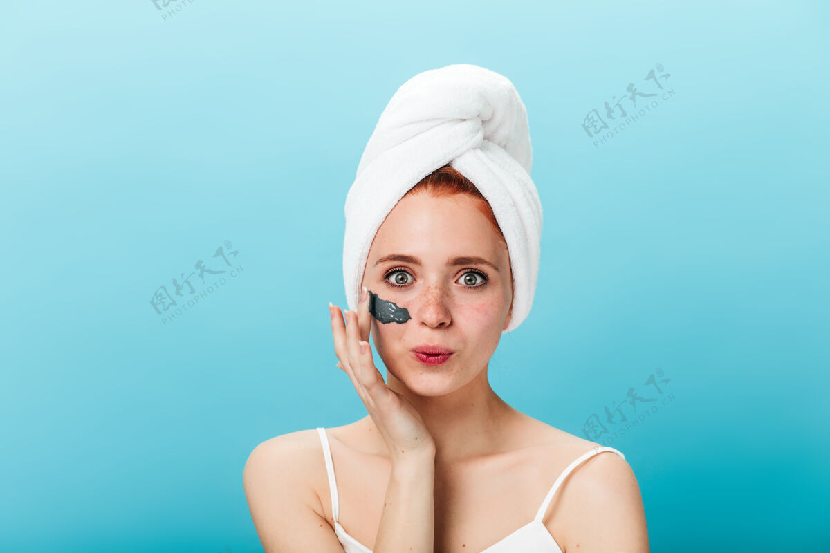 蓝色隔离热情的女孩在敷面膜摄影棚拍摄的快乐女人在做水疗 在蓝色背景下微笑护理完美的皮肤面部