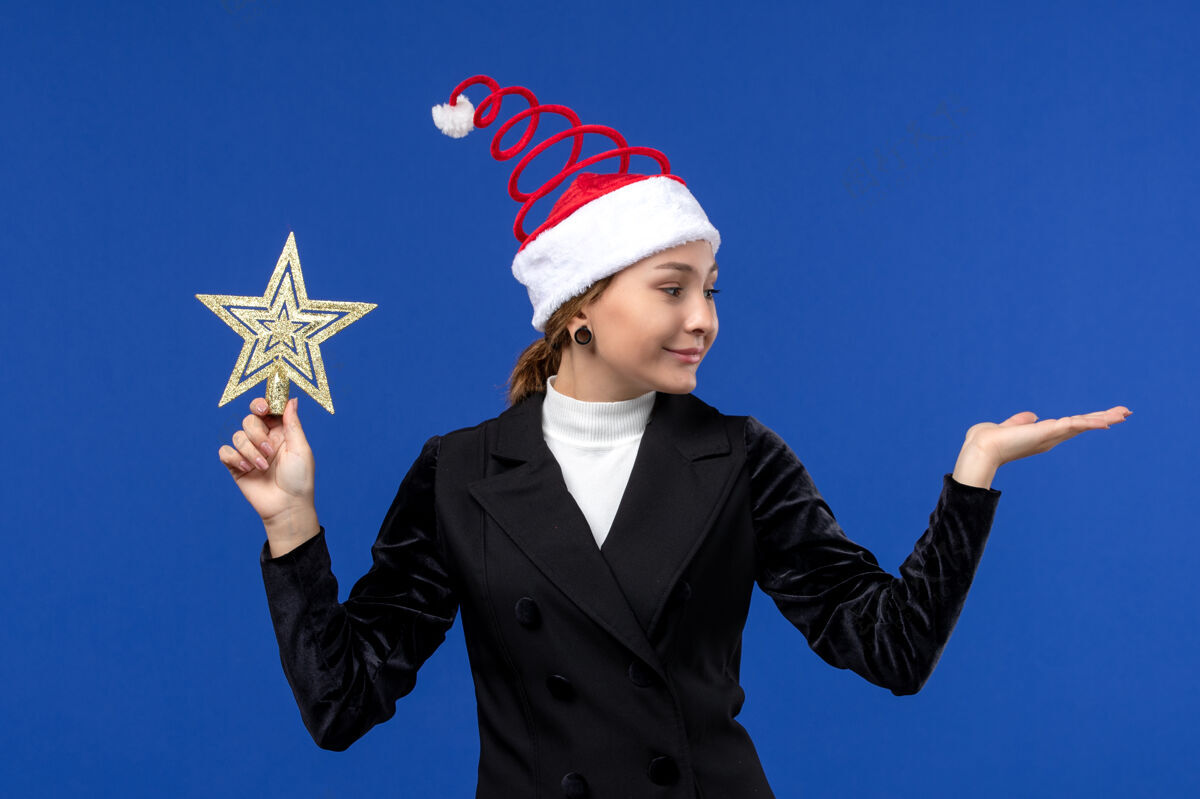 西装正面图年轻女子手持星形玩具在蓝色墙壁上过年明星圣诞节英俊
