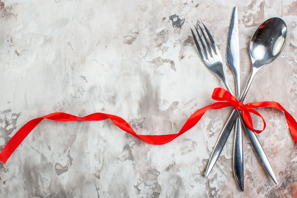 食品顶视图银色餐具与红色蝴蝶结在灯光表面笔厨房羽毛笔