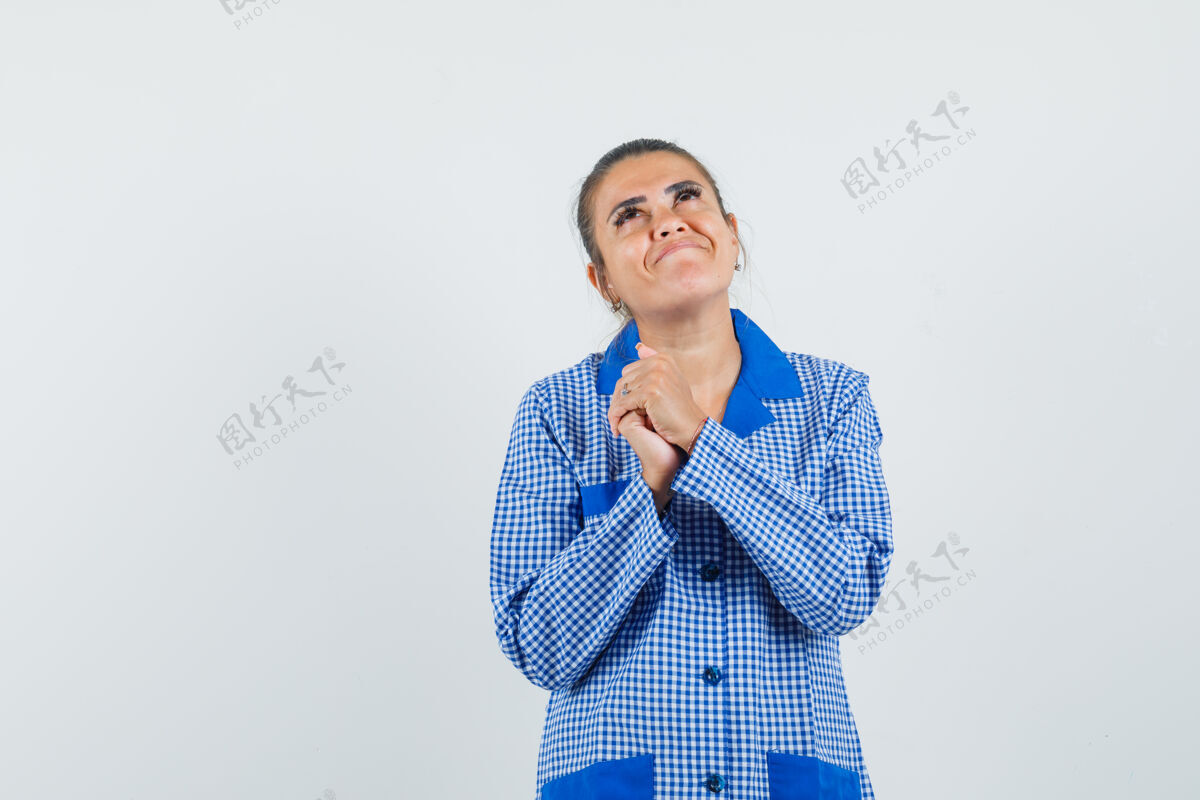 梦年轻女子手牵手祈祷的姿势 梦想着什么东西在蓝色方格睡衣衬衫 看起来很漂亮前视图祈祷衬衫姿势