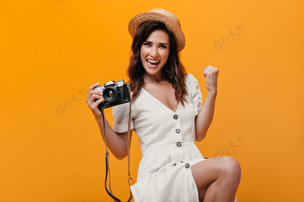 衬衫美丽的女孩高兴地看着橙色背景的相机快乐的女人穿着白色时装 大纽扣微笑着室内情感脸