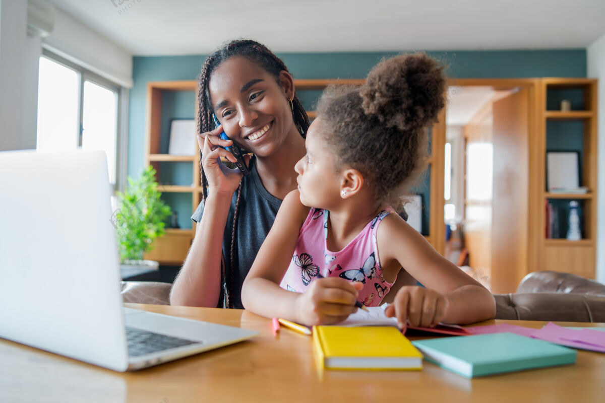 学校妈妈一边在家里打电话 一边帮助和支持女儿上网络学校新的正常生活方式理念单亲观念孩子父母家庭作业