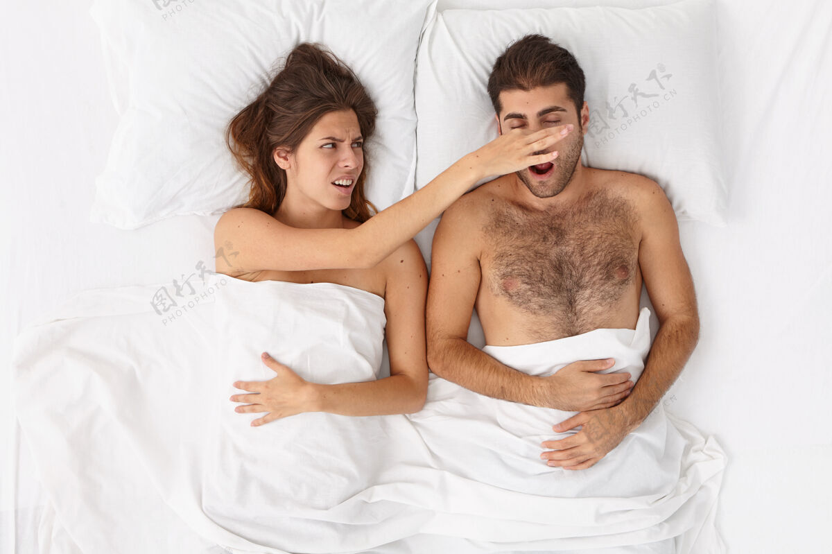 枕头特写这对躺在床上白毯子下的夫妇生活方式睡眠噪音