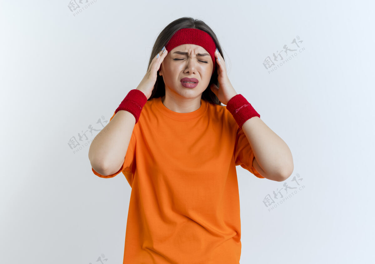 腕带戴着头带和腕带的年轻运动女性患有头痛 闭着眼睛隔离在白色墙壁上 留有复印空间痛苦封闭戴