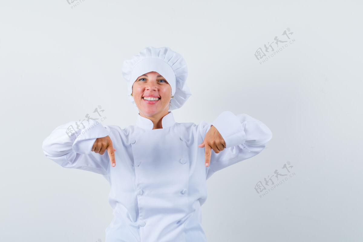 护理穿着白色厨师制服的金发女人用食指指着下面 看起来很漂亮制服健康时尚