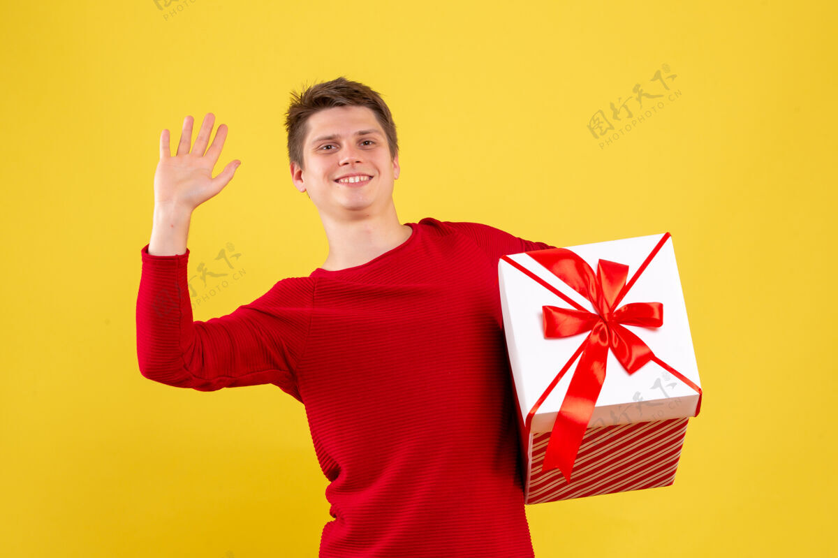 大正面图黄色背景上有大圣诞礼物的年轻男性成人圣诞礼物