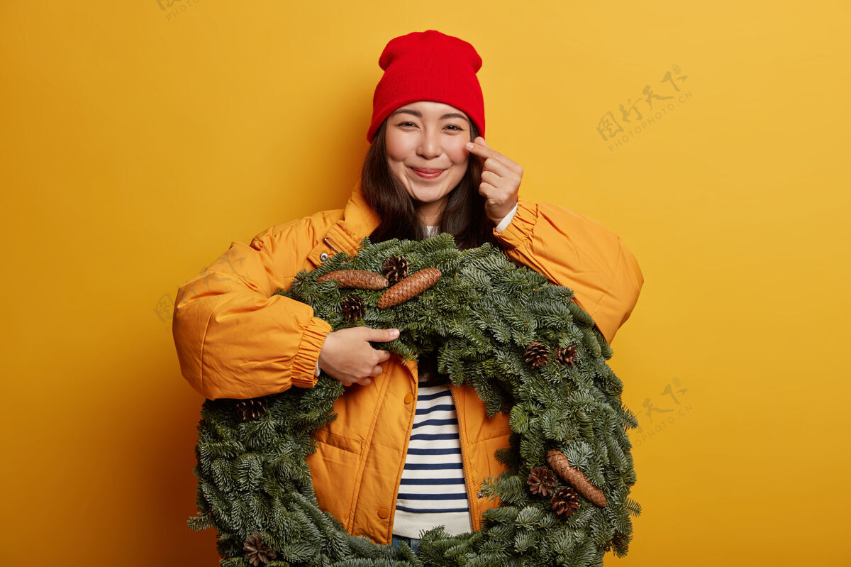 条纹快乐少女制作韩式标牌 表达爱意 戴红帽 穿外套 手拿绿色手工花圈 准备过圣诞节积极黑发节日