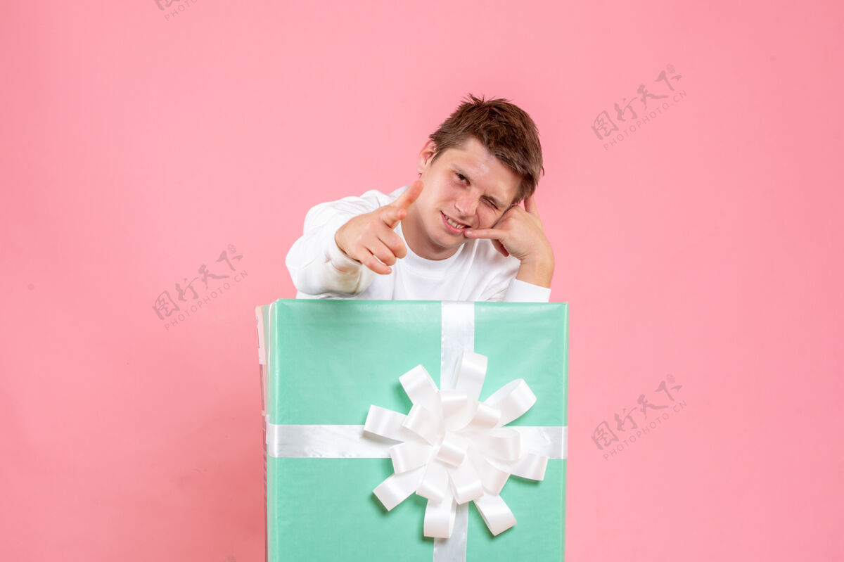 正面正面图粉色背景上穿着白衬衫的年轻男性情感圣诞节丝带