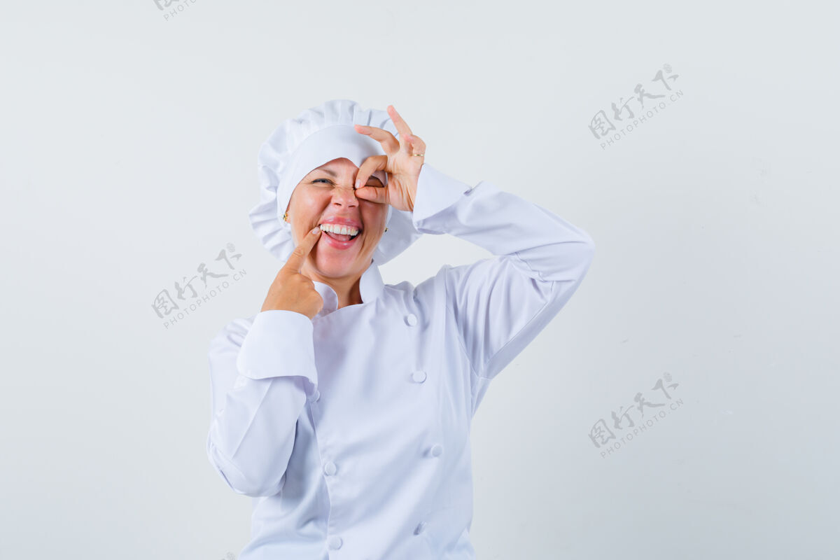 女士一位身穿白色制服的女厨师在眼睛上显示“ok”标志 看上去很乐观优雅制服乐观
